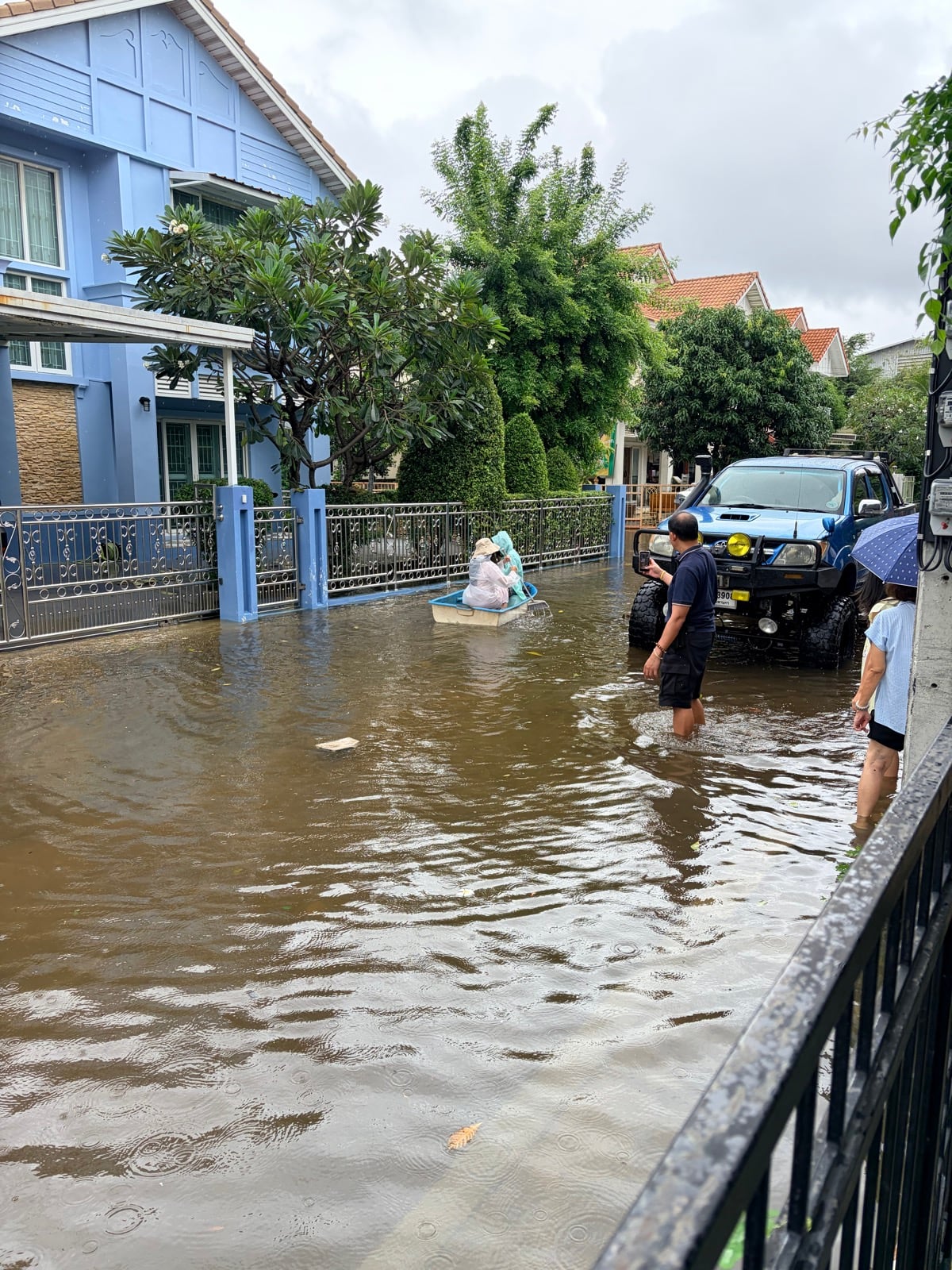 积水中的社区道路，小舟与皮卡停在家门外